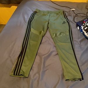 Adidas green sweatpants with black stripes on the side zipper from ankle to calf